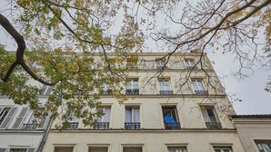 A multi-story building with balconies, windows, and a tree in the foreground. - Beautiful Renovated Apartment With AC - Paris East (Paris)