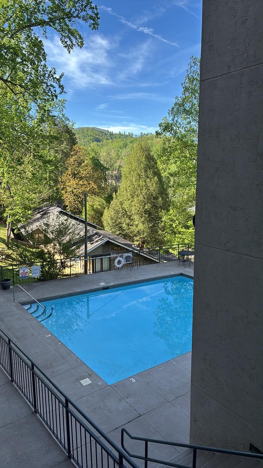 Una piscina con vistas a un área boscosa y un edificio con tejado inclinado.