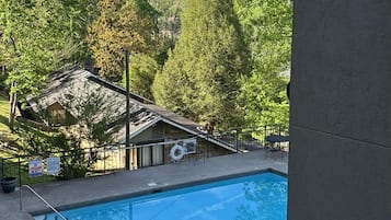 Una piscina con vistas a un área boscosa y un edificio con tejado inclinado.