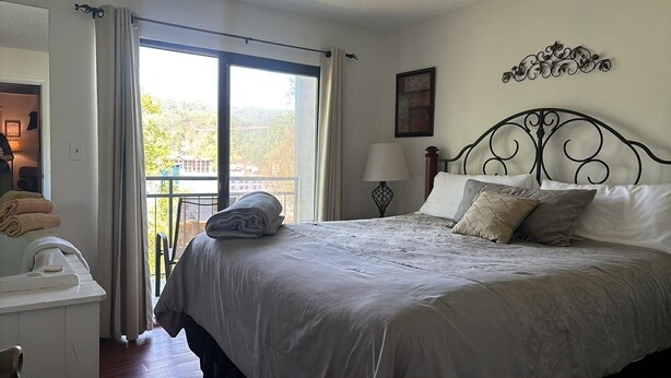 A bedroom with a bed, a nightstand, a lamp, and a view of the outdoors. - Lovely Private Apartment with Pool in Walking Distance to Downtown Gatlinburg. (Gatlinburg)