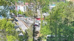 A wooden deck with a view of a parking lot and buildings in the background. - Lovely Private Apartment with Pool in Walking Distance to Downtown Gatlinburg. (Gatlinburg)