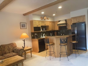 A kitchen with wooden cabinets, a black refrigerator, and a bar area with stools. - Perfect 2-bedroom townhome in pleasant Park City neighborhood (Park City)