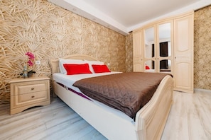 Un dormitorio con cama, mesita de noche, armario y pared decorada.