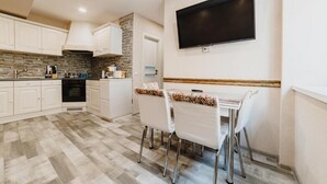 Una cocina moderna con gabinetes blancos, un salpicadero de piedra y un comedor con una mesa y sillas.