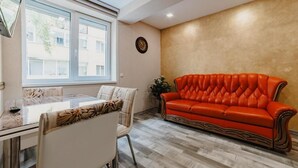 Un comedor con una mesa de vidrio, sillas y un sofá de cuero rojo frente a una pared con textura.