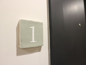 A white wall with a white number '1' sign. - Albertina Studio (Porto)