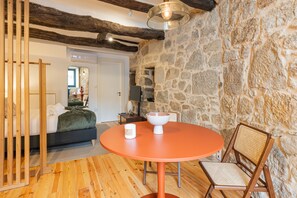 Ein Zimmer mit einer Steinsandsteinwand, einem runden orangefarbenen Tisch, einer Couch und einem Holzboden.