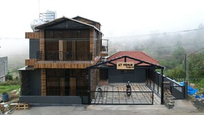 Een gebouw met twee verdiepingen, een balkon, een bord waarop 'AT VENUE Groups LLP' staat, en een scooter die ervoor geparkeerd staat.