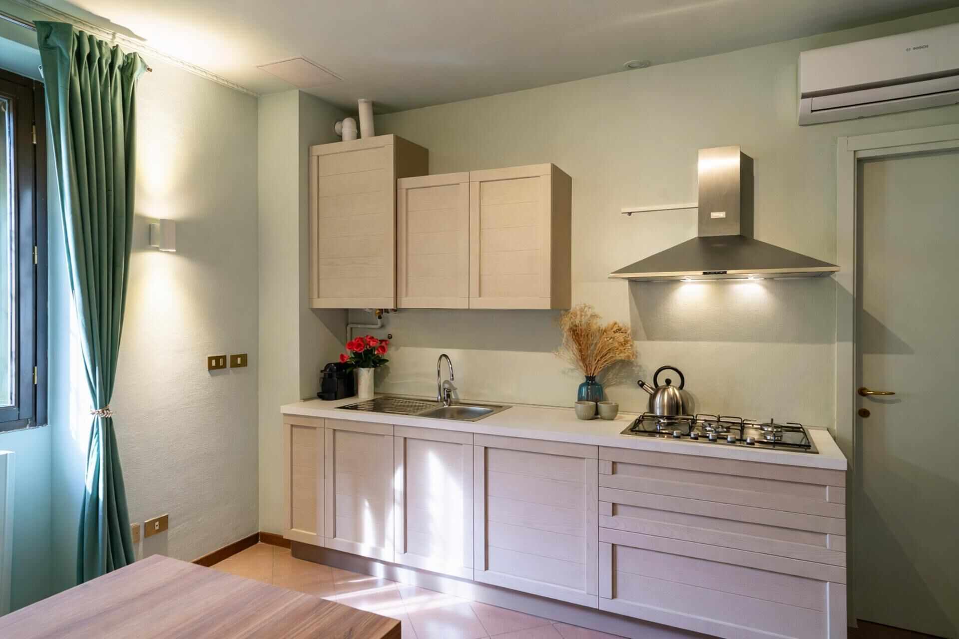 Een kleine keuken met een gasfornuis, een spoelbak en kastjes.