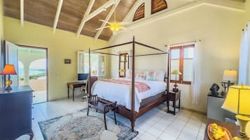 A four-poster bed with a wooden frame, a large rug, and a desk with a lamp.
