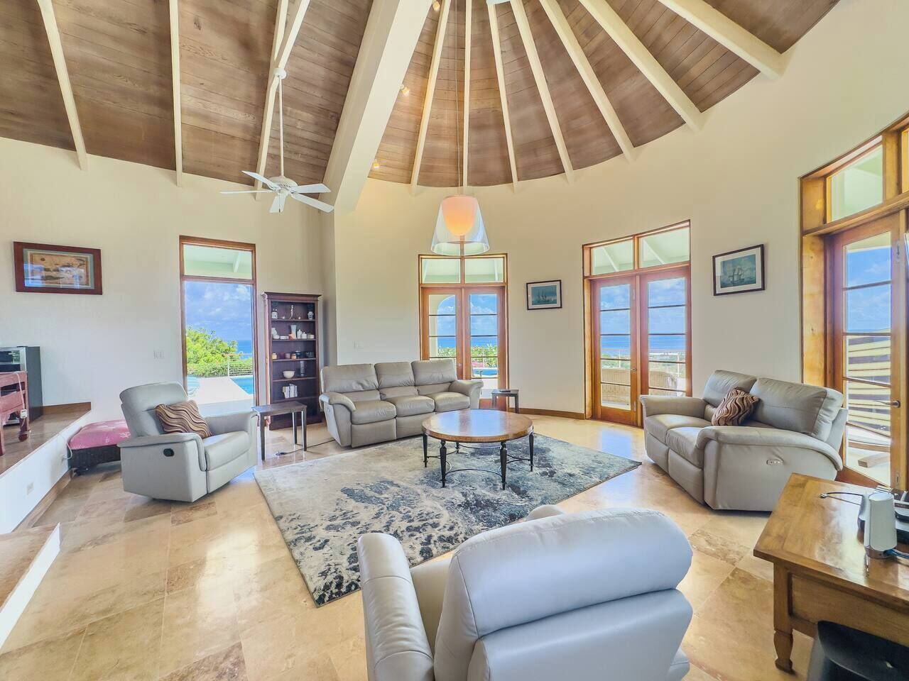 A spacious living room with a high ceiling, multiple seating areas, and large windows providing views.