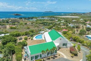 A large building with a green roof, a swimming pool, and a view of the ocean. - Buck Island Views | Private Pool & 3 Bedroom Suites (Christiansted)
