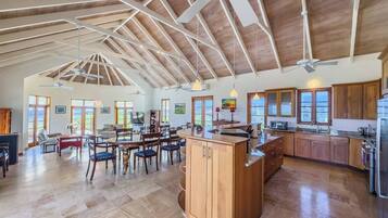 A spacious kitchen with wooden cabinets, a central island, and a dining area with chairs and a table.