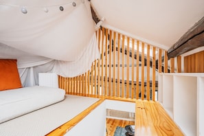 A cozy loft bedroom with a bed, a sofa, and a wooden staircase. - Albertina Mezzanine 4 Studio (Porto)