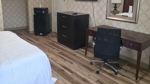 A hotel room with a bed, a desk, a chair, a television, a dresser, and a mirror. - DOVER INN (Dover)