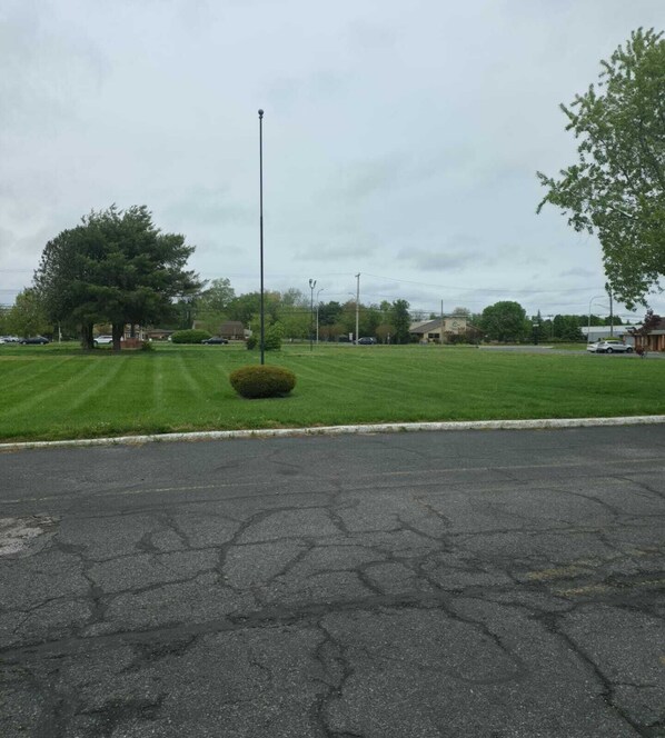A parking lot with a grassy area, a tall streetlight, and a few buildings in the background.