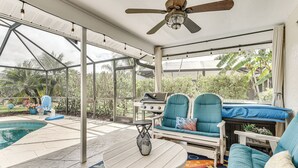 Un patio techado al aire libre con piscina, zona de estar y ventilador de techo.