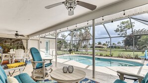 Zona junto a la piscina con un porche cubierto, asientos y vistas a una piscina.