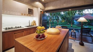 Een moderne keuken met een centraal eiland, een zithoek buiten en uitzicht op een tuin.