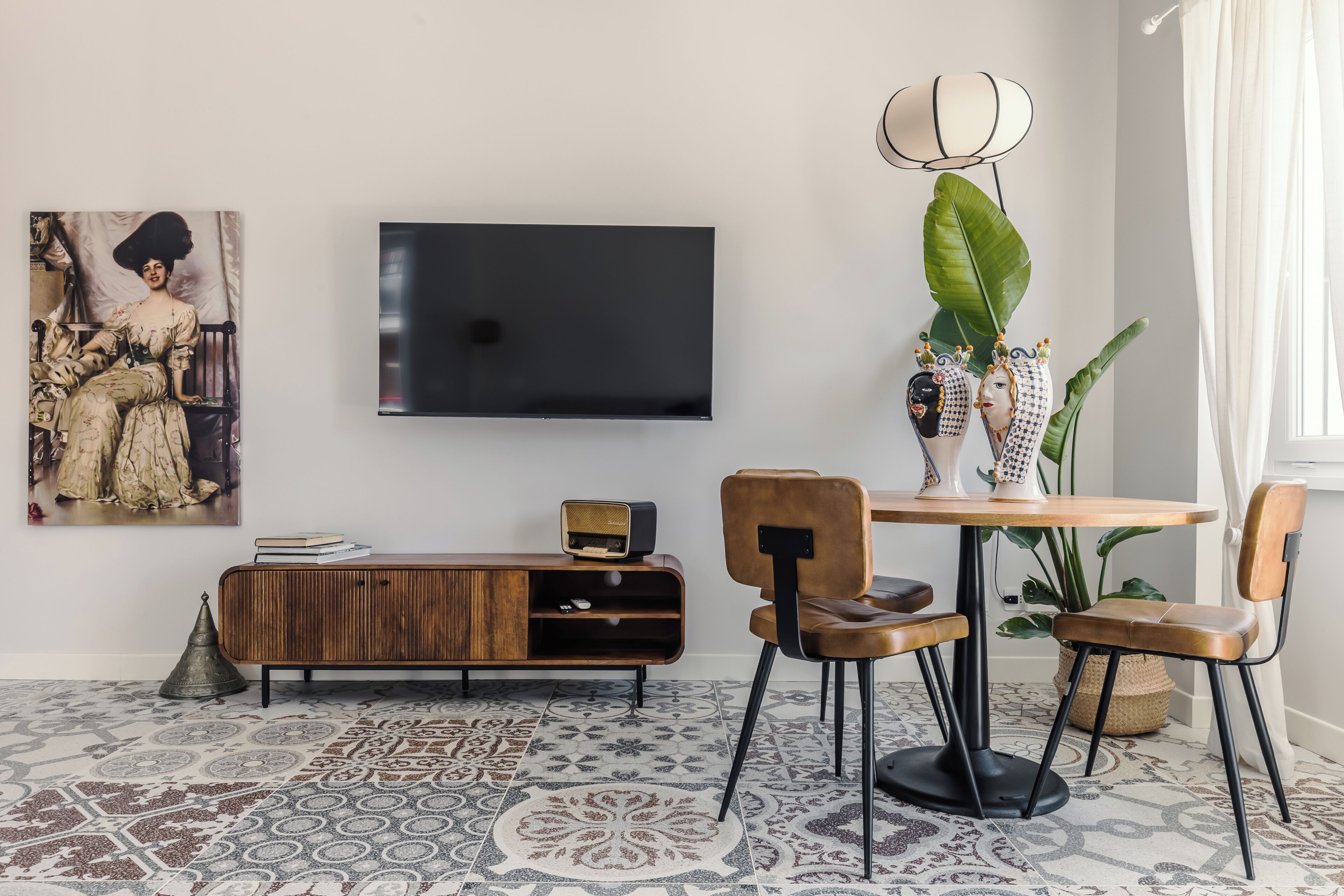 Un salon moderne avec un téléviseur à écran plat, un meuble en bois, une table à manger avec des chaises et une grande plante.