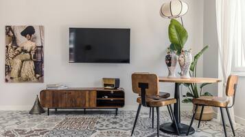 Un salon moderne avec un téléviseur à écran plat, un meuble en bois, une table à manger avec des chaises et une grande plante.