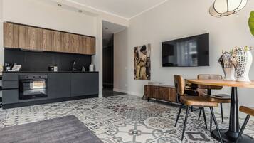 Une cuisine moderne avec des meubles de couleur sombre, un four encastré et un coin repas comprenant une table et des chaises en bois.