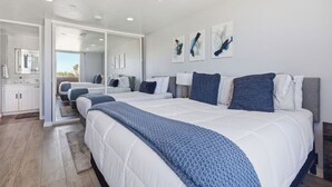 A modern bedroom with a large bed, a walk-in closet, and a bathroom with a large mirror. - Oceanfront Oasis in Pacific Beach  Walk to PB Pier  Pool Monthly Rental (San Diego)