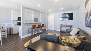 A modern living room with a sofa, coffee table, and a TV mounted on the wall. - Oceanfront Oasis in Pacific Beach  Walk to PB Pier  Pool Monthly Rental (San Diego)