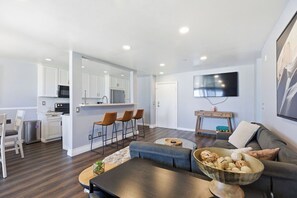 A modern living room with a sofa, coffee table, and a TV mounted on the wall. - Oceanfront Oasis in Pacific Beach  Walk to PB Pier  Pool Monthly Rental (San Diego)