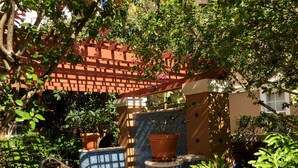 Een zwembadgedeelte met een betegelde mozaïekwand, potplanten en een pergola.