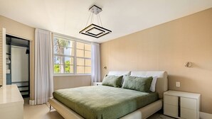 Een slaapkamer met een bed, nachtkastjes, een kledingkast en een raam met gordijnen.