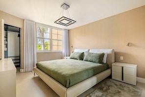 Ein Schlafzimmer mit Bett, Nachttischen, einem Kleiderschrank und einem Fenster mit Vorhängen.
