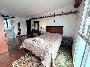 A bedroom with a bed, bedside table, dresser, and a mirror.