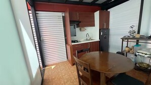 Une cuisine de taille réduite comprenant une table à manger, des placards et un réfrigérateur.