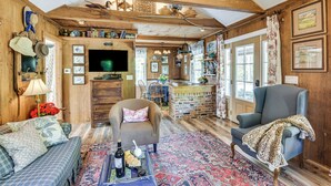 Un ambiente rustico con travi in legno, una televisione, un'area pranzo e un tappeto decorato.