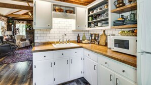 Una cucina con mobili bianchi, un piano di lavoro in legno e un forno a microonde.
