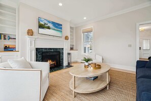 Un salon avec une cheminée, une table basse ronde, un canapé et une bibliothèque.