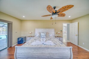 Una camera da letto con un letto, un ventilatore a soffitto, un comodino e una porta con vista attraverso una porta di vetro.