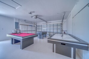 Una stanza con tavolo da biliardo, tavolo da calcio e parete a specchio.
