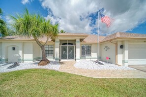 Una casa a due piani con un ingresso principale, un garage e un palo con la bandiera americana.