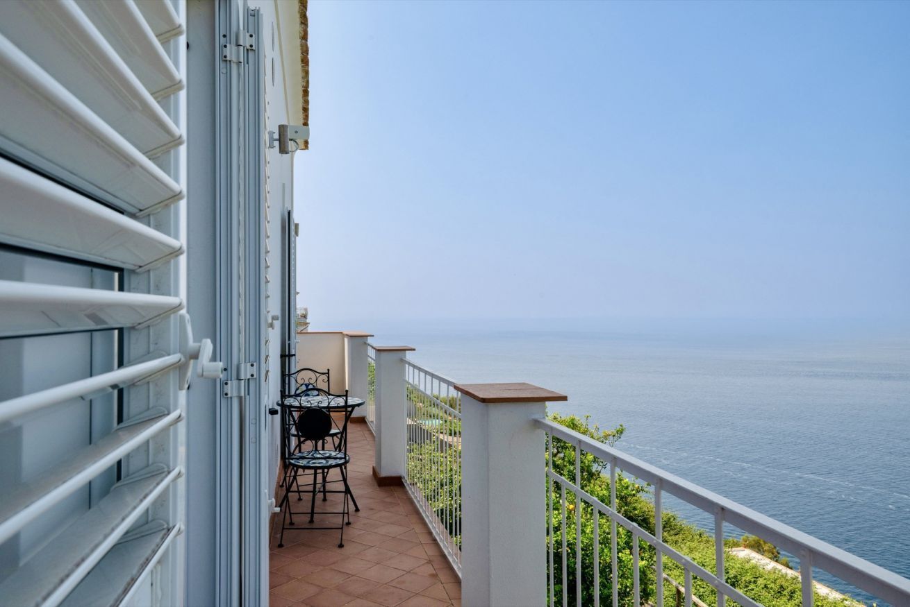 A balcony with a table and chairs, overlooking a body of water.