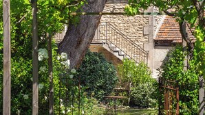 A garden with a pergola, a stone building with a staircase, and a clear blue sky. - Mas Du Tilleul (Saint-Rémy-de-Provence)