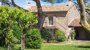A stone house with a tiled roof, a staircase, and a garden with trees and shrubs. - Mas Du Tilleul (Saint-Rémy-de-Provence)