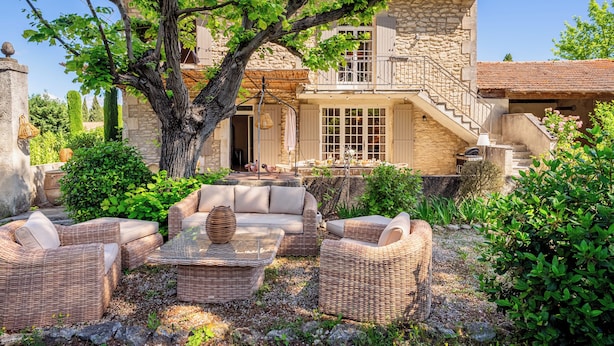 A stone house with a balcony, outdoor seating, and a large tree. - Mas Du Tilleul (Saint-Rémy-de-Provence)