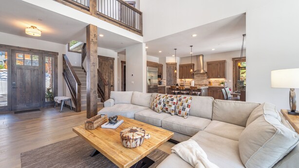 A spacious living area with a large sofa, a wooden coffee table, and a staircase leading to an upper level. - Fairway Estate: Hot Tub, Fire Pit & Dog Friendly (Truckee)