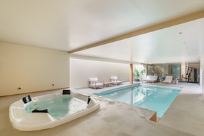 A modern indoor pool with a hot tub, lounge chairs, and exercise equipment. - The Ehrlich Essence Villa by Minho s Guest (Braga)