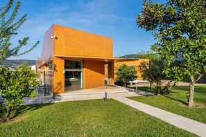 Un bâtiment moderne doté d’un toit plat, de grandes fenêtres et d’un espace d’entrée pavé.