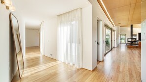 Ein geräumiger Korridor mit Holzboden, weißen Wänden und großen Fenstern.