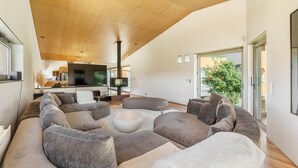 Ein modernes Wohnzimmer mit einer großen Eckcouch, einem Couchtisch und einem Fernseher im Hintergrund.