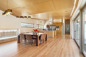 A spacious kitchen with modern appliances, a dining area with a wooden table and chairs, and large windows providing natural light. - The Ehrlich Essence Villa by Minho s Guest (Braga)